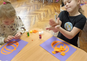 dzieci wyklejają bibułą sylwetę dyni