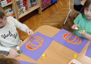 dzieci wyklejają bibułą sylwetę dyni
