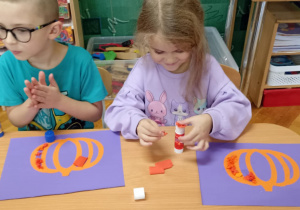 dzieci wyklejają bibułą sylwetę dyni