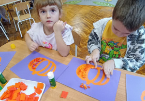 dzieci wyklejają bibułą sylwetę dyni