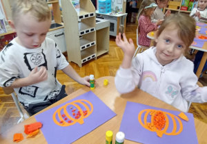 dzieci wyklejają bibułą sylwetę dyni