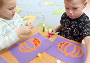 dzieci wyklejają bibułą sylwetę dyni