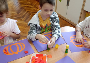 dzieci wyklejają bibułą sylwetę dyni