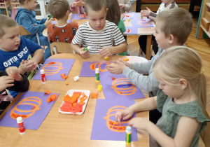 dzieci wyklejają bibułą sylwetę dyni