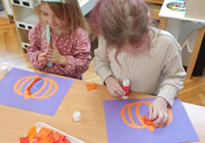 dzieci wyklejają bibułą sylwetę dyni