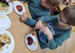 Dzieci wykonują jeżyki z owoców