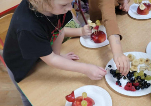 Dzieci wykonują jeżyki z owoców