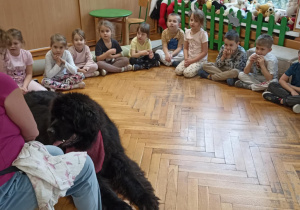 dzieci siedzą w kole przy psie