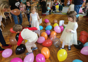 dzieci z rodzicami tańczą z balonami
