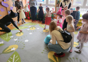 dzieci z rodzicami stoją na dywanie