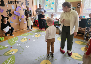 dzieci z rodzicami stoją na dywanie