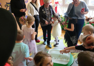 dzieci z rodzicami stoją na dywanie