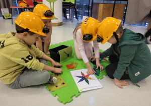 dzieci siedzą w kaskach i układają