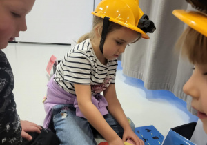 dzieci siedzą w kaskach i układają