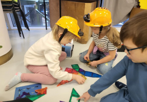 dzieci siedzą w kaskach i układają
