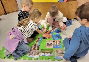 dzieci siedzą na macie i układają obrazki