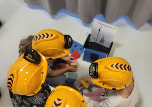 dzieci siedzą w kaskach i układają