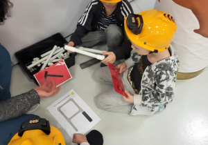 dzieci siedzą w kaskach i układają