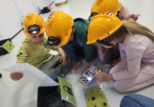 dzieci siedzą w kaskach i układają