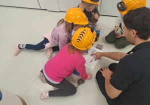 dzieci siedzą w kaskach i układają