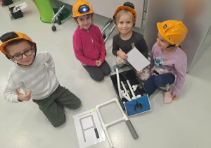 dzieci siedzą w kaskach i układają