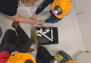 dzieci siedzą w kaskach i układają