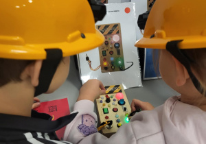 dzieci siedzą w kaskach i układają