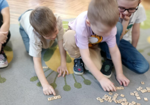 dzieci układaja napis z liter