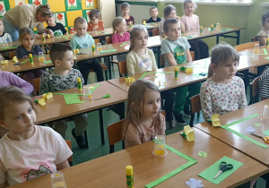 dzieci siedzą w ławkach