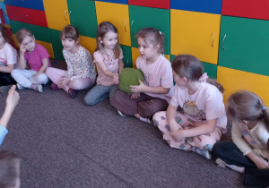 dzieci siedzą w kole na dywanie