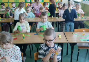 dzieci siedzą w ławkach