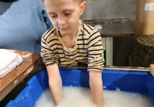 chłopiec zanurza ręce w wodzie