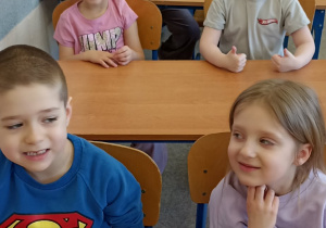 dzieci siedzą w ławce