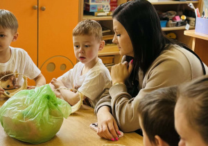 Dzieci z rodzicami wykonują koszyczki wielkanocne