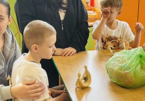 Dzieci z rodzicami wykonują koszyczki wielkanocne