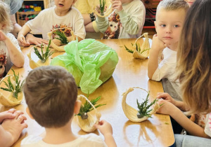 Dzieci z rodzicami wykonują koszyczki wielkanocne