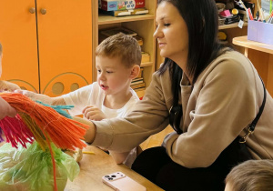 Dzieci z rodzicami wykonują koszyczki wielkanocne