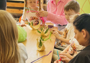 Dzieci z rodzicami wykonują koszyczki wielkanocne