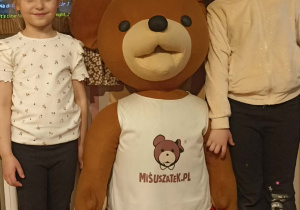 dzieci stiją przy misiu
