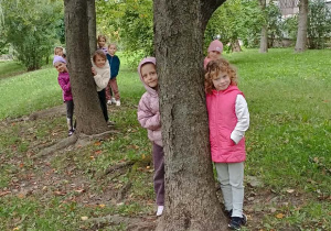 dzieci wyglądają zza drzewa