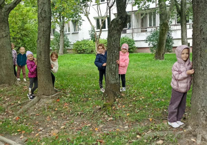 dzieci wyglądają zza drzewa