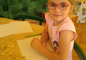 Dziewczynka układa klocki z literami