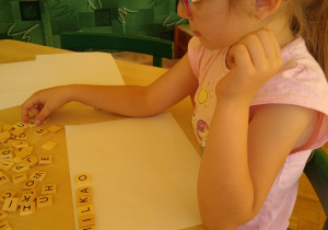 Dziewczynka układa klocki z literami