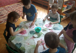 Dzieci przyklejają kulki z bibuły.