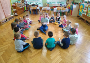 Dzieci siedzą z nauczycielką na podłodze