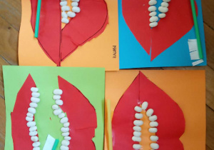 Prace plastyczne przedstawiające papierowe usta i "zęby" naklejone z fasol