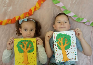 Dzieci pokazują swoje jesienne drzewa.