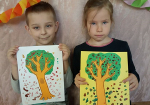 Dzieci pokazują swoje jesienne drzewa.