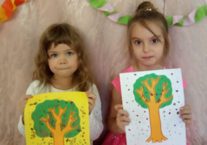 Dziewczynki pokazują swoje jesienne drzewa.