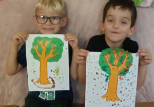 Chłopcy pokazują swoje jesienne drzewa.